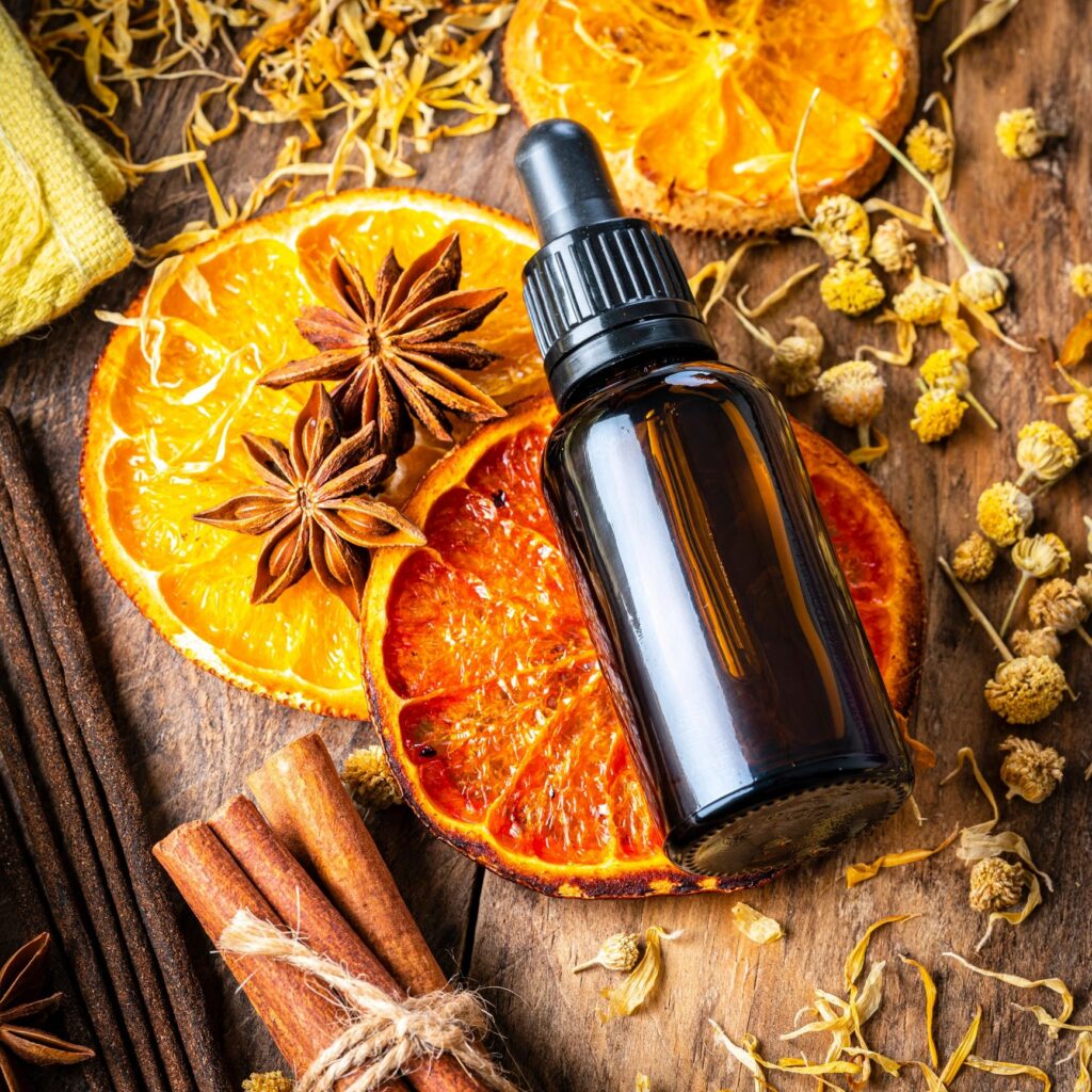 Aromarherapy: essential oil bottle, incense, dried oranges and scented spices on wooden table