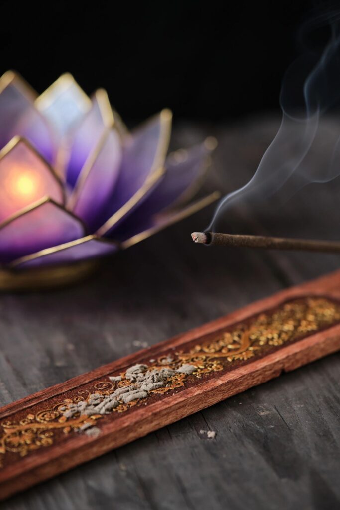 Close-up of a burning incense stick on an wooden incense holder with beautiful smoke. Dark and moody still life, zen concept.